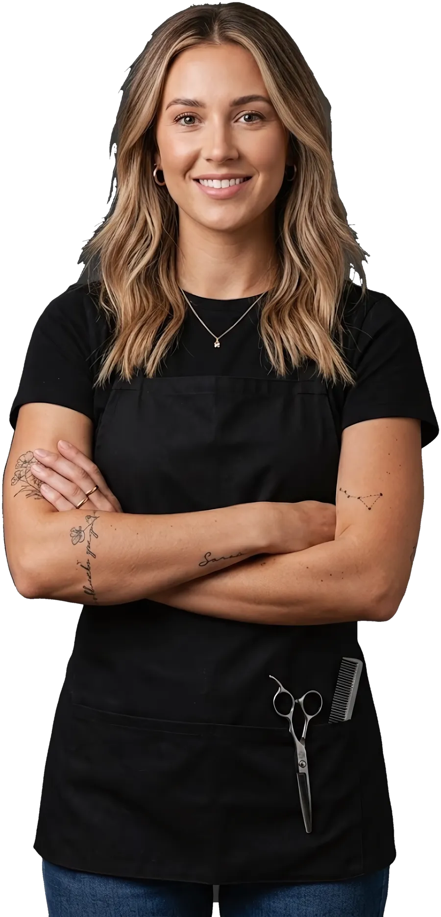 A hairdresser in a black apron, arms crossed, smiling